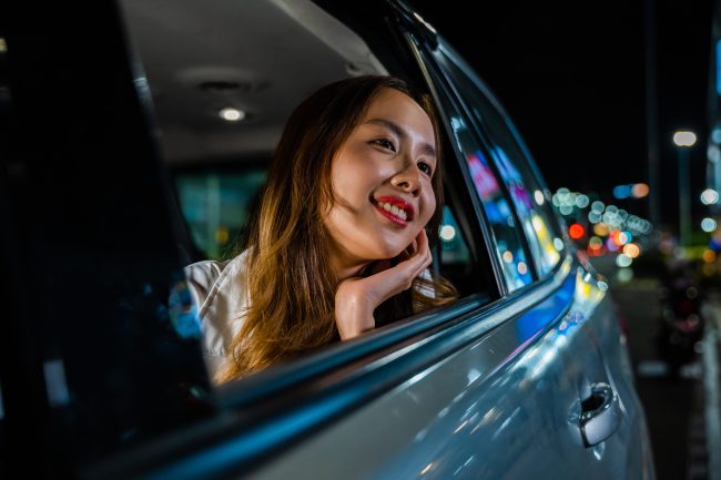 A woman looking up in the back seat of a car in the evening.